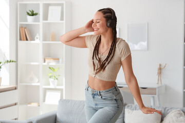 Young woman with dreadlocks in headphones at home