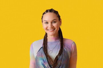 Fashionable young woman with dreadlocks smiling on yellow background
