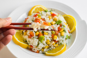 Rice salad or pilaf with colorful vegetables from Asian cuisine.,served with sliced lemon and chopsticks
