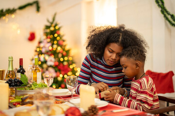 A cheerful holiday dinner scene with a diverse family enjoying a festive meal. Christmas decorations, gifts, and a lit Christmas tree create a cozy atmosphere, enhancing the warmth of the celebration.