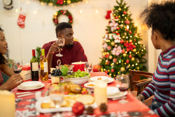 A warm Christmas family dinner with a father serving food to his young child, surrounded by festive decorations, a Christmas tree, and a holiday table spread. Joyful and cozy holiday atmosphere.