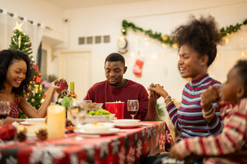 A warm Christmas family dinner with a father serving food to his young child, surrounded by festive decorations, a Christmas tree, and a holiday table spread. Joyful and cozy holiday atmosphere.