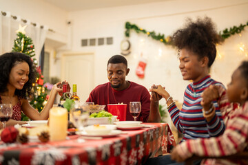 A warm Christmas family dinner with a father serving food to his young child, surrounded by festive decorations, a Christmas tree, and a holiday table spread. Joyful and cozy holiday atmosphere.
