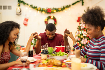 A family enjoys a festive Christmas dinner, sharing food and creating memories. A beautifully decorated Christmas tree and wreath add warmth, while candles and decor enhance the cozy holiday setting.