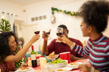 A joyful family shares a Christmas meal together, passing food and creating holiday memories. Decorated tree, festive lights, and presents in the background add warmth to cozy celebration atmosphere.