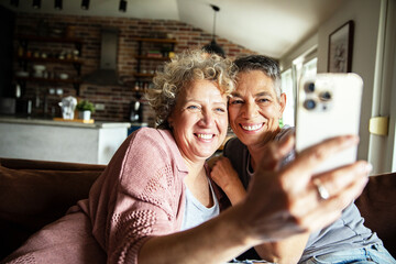 Happy senior lesbian couple relaxing on couch at home