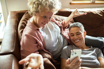 Happy senior lesbian couple relaxing on couch at home