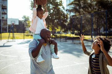 Family playing basketball together on outdoor court