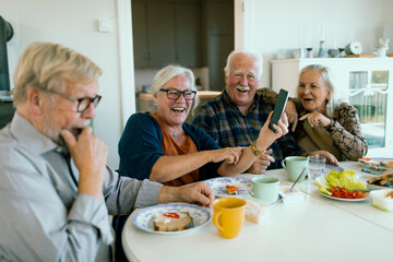 Group of happy seniors laughing during breakfast at home