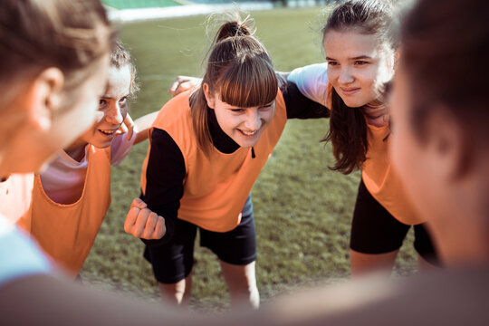 Teen soccer team huddling before match on outdoor field