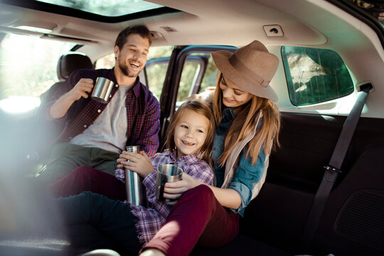 Family road trip enjoying hot drinks in the back of SUV