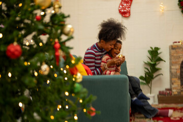 An African American family gathers for a festive Christmas party, enjoying snacks, drinks, and laughter in their decorated living room. Concept for holiday entertaining and joyful feasts.