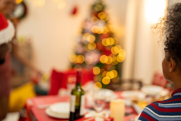 An African American family gathers for a festive Christmas party, enjoying snacks, drinks, and laughter in their decorated living room. Concept for holiday entertaining and joyful feasts.