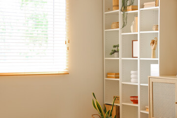 Interior of living room with dresser and shelving units near window