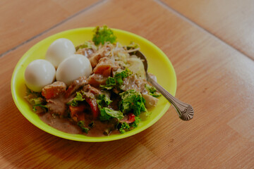 Javanese vegetable salad with peanut sauce (gado-gado) served with three egg, ceramics background. Copy space.