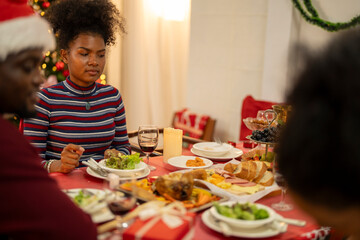 An African American family gathers for a festive Christmas party, enjoying snacks, drinks, and laughter in their decorated living room. Concept for holiday entertaining and joyful feasts.