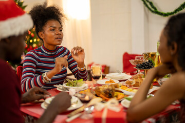An African American family gathers for a festive Christmas party, enjoying snacks, drinks, and laughter in their decorated living room. Concept for holiday entertaining and joyful feasts.