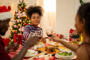 An African American family gathers for a festive Christmas party, enjoying snacks, drinks, and laughter in their decorated living room. Concept for holiday entertaining and joyful feasts.