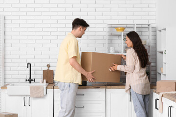 Young couple putting parcel box on counter in kitchen