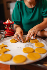 Close-up of woman arranging raw cookies on a baking tray at home