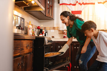 Mother and teenage son reacting to burnt cookies in Christmas kitchen