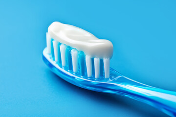 Toothbrush with white toothpaste close-up on blue background