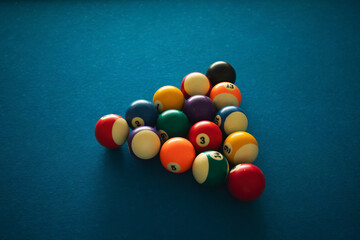 Colorful billiard balls are set up for a game on a blue surface