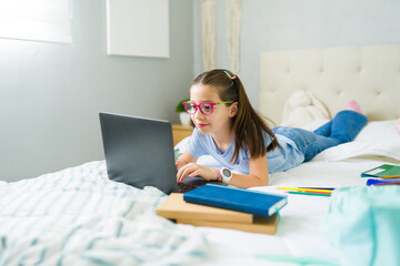 Preteen girl using laptop for online education at home