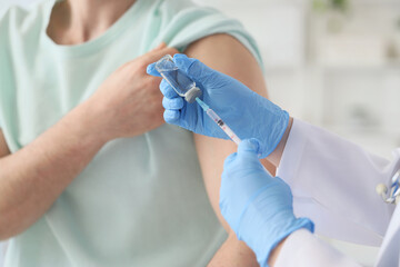 Doctor vaccinating man in clinic, closeup