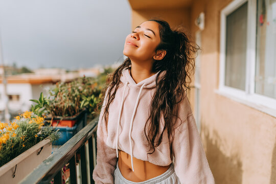 Young woman enjoying fresh morning air on apartment balcony - Powered by Adobe