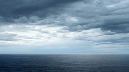 Fototapeta premium A vast ocean under a dramatic, cloudy sky with layers of dark and light clouds stretching toward the horizon.