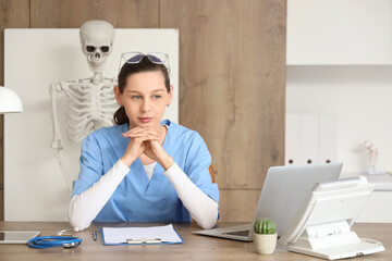 Female medical intern studying at table in clinic