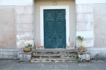 Inviting entrance to an aged Tuscan Villa, with a rustic door and weathered stone steps, bathed in...