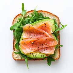Single slice of avocado toast in the shape of classic sandwich bread (rounded top, rectangular bottom), topped with thin slices of smoked salmon and fresh arugula leaves. 