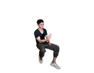 A young man in casual attire is captured mid-air in a squatting pose, looking down at his hands against a white background.