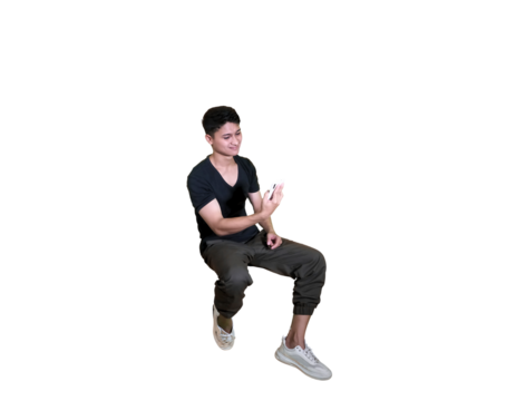 A young man in casual attire is captured mid-air in a squatting pose, looking down at his hands against a white background.