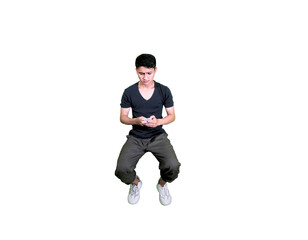 A young man dressed casually is sitting while holding a cellphone.