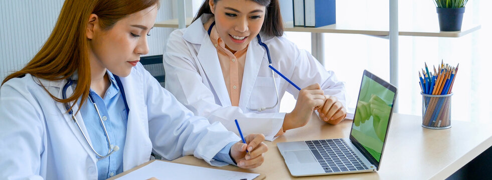 Banner hands of two women doctor medical lab discussing together healthcare teamwork. Panorama Two asian women doctors meeting write prescription medical clinic office using laptop with copy space.