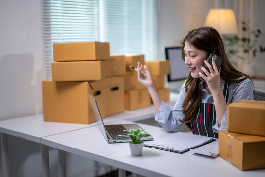 Online seller talking on phone and managing online orders on laptop