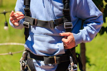 Close-up of person adjusting black harness in outdoor setting