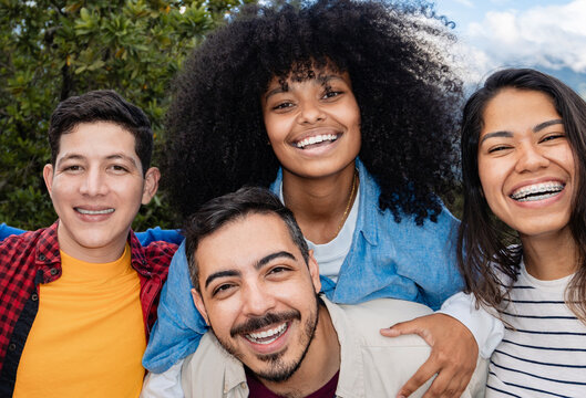 Multiracial friends smiling at camera outdoors – Diverse young people having fun together on urban street – Youth and lifestyle concept