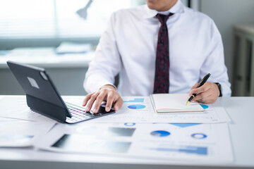A man is sitting at a desk with a laptop and a notebook