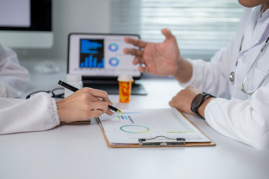 Two doctors are discussing a patient's medical data on a table