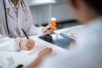 A doctor is holding a bottle of pills in front of a patient