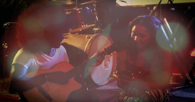 Musicians strumming guitar invoking lens flares while adding shaker percussion synchronizing groove