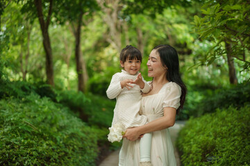 happy mother holding and talking with toddler girl in garden