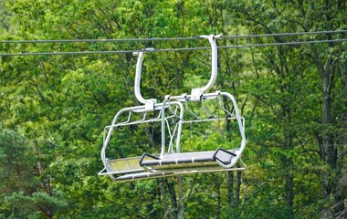 Empty ski lift car suspended amidst lush green forest canopy near Camelback Mountain, Tannersville, Pennsylvania, U.S.