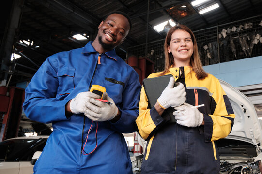 Happy professional teamwork, White female inspector engineer and Black mechanic man cheerful, arms crossed with smile in fix car garage, maintenance service jobs in automotive transportation industry.