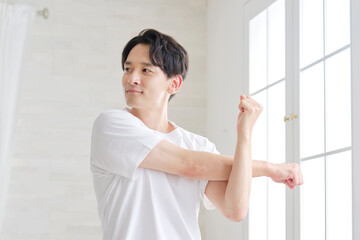 自宅で腕のストレッチする男性