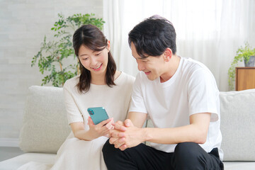 リビングでスマホを使うカップル